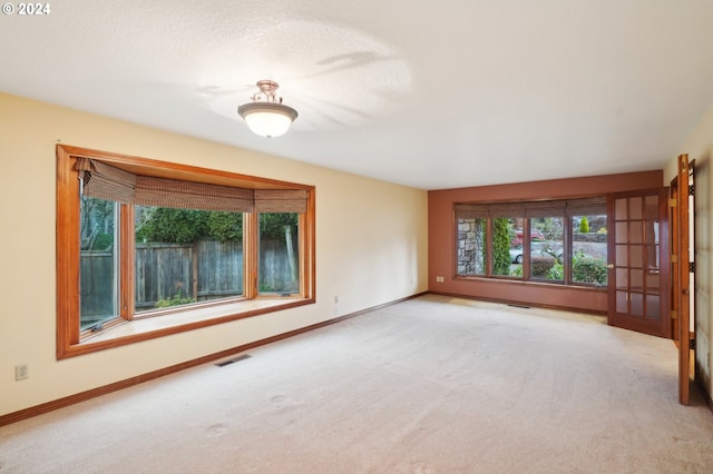 unfurnished living room with light carpet and a textured ceiling