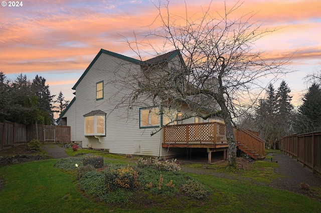 back house at dusk with a yard and a deck