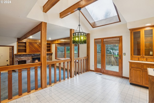 entrance foyer with vaulted ceiling with skylight, a fireplace, and an inviting chandelier