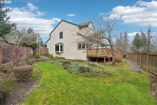 rear view of house with a wooden deck and a lawn