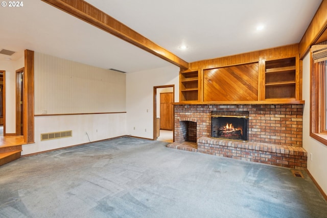 unfurnished living room featuring carpet, built in shelves, wooden walls, beam ceiling, and a fireplace