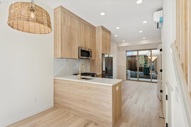 kitchen with appliances with stainless steel finishes, sink, backsplash, light wood-type flooring, and kitchen peninsula