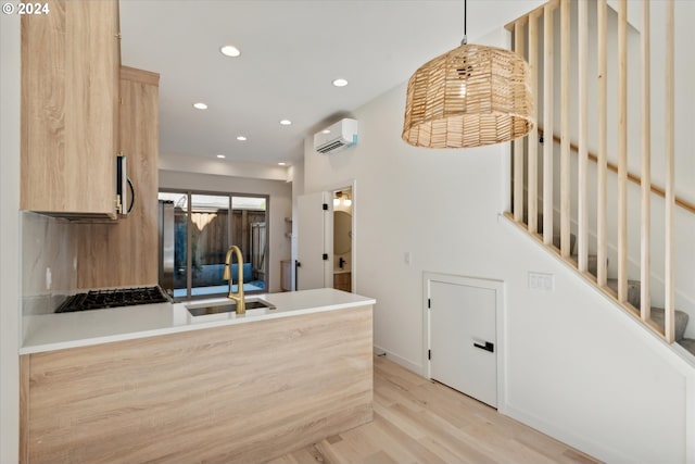 kitchen featuring hanging light fixtures, light hardwood / wood-style flooring, sink, black gas cooktop, and a wall mounted AC