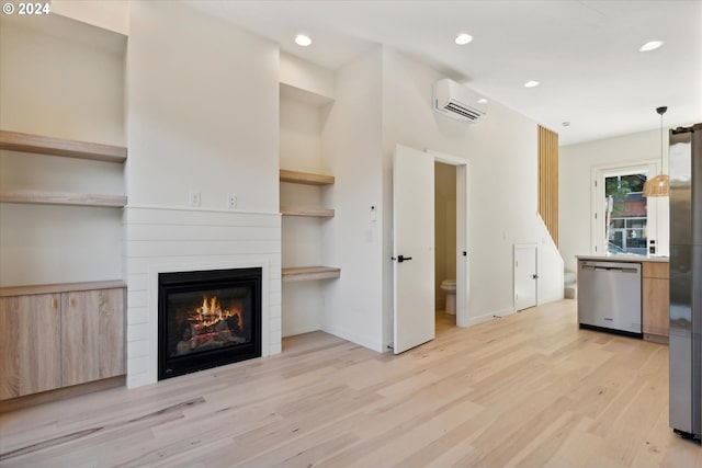 unfurnished living room featuring a large fireplace, light hardwood / wood-style floors, and a wall mounted AC