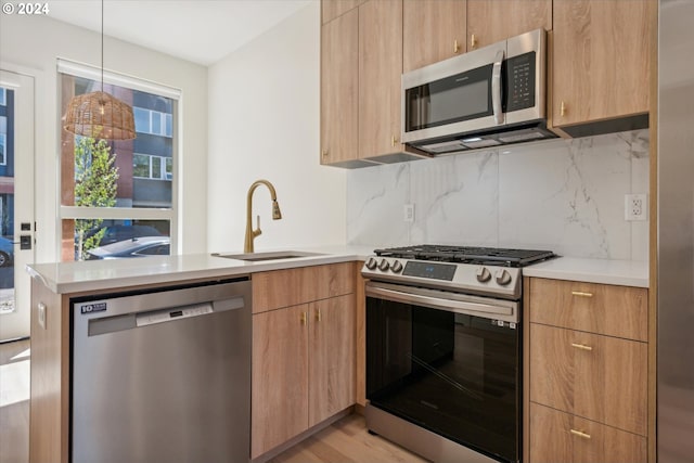 kitchen with decorative light fixtures, backsplash, stainless steel appliances, light hardwood / wood-style floors, and sink