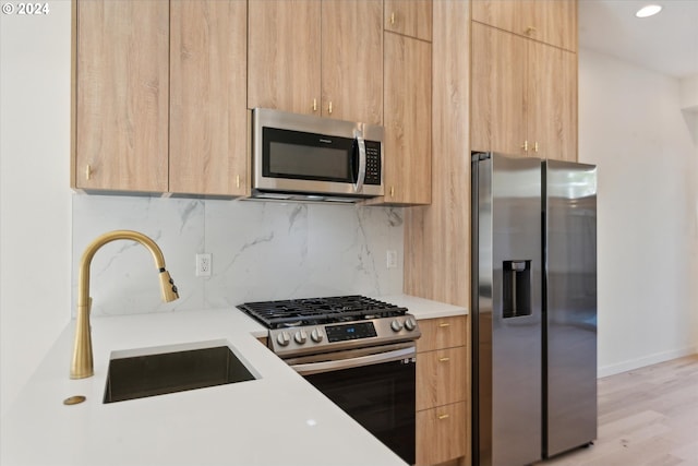 kitchen featuring light brown cabinets, appliances with stainless steel finishes, light hardwood / wood-style flooring, backsplash, and sink