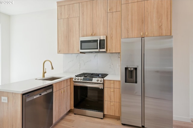 kitchen featuring tasteful backsplash, appliances with stainless steel finishes, light hardwood / wood-style flooring, and sink