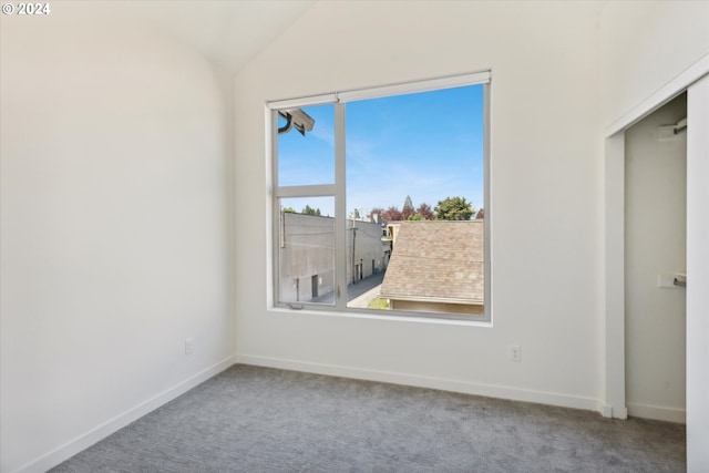 carpeted empty room featuring vaulted ceiling