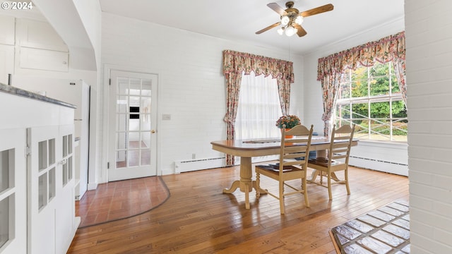 dining area featuring brick wall, ceiling fan, light wood-style flooring, and a baseboard radiator