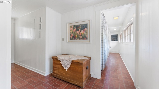 hallway with wood walls, brick patterned floor, and baseboards
