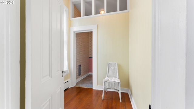 corridor with dark hardwood / wood-style flooring and baseboard heating