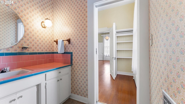 bathroom with hardwood / wood-style flooring, vanity, and backsplash