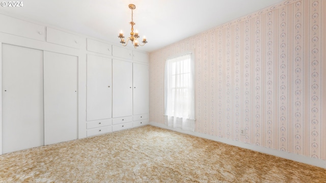 unfurnished bedroom with carpet floors, an inviting chandelier, and a closet