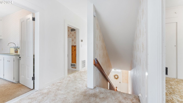 corridor with baseboards, light carpet, an upstairs landing, and visible vents