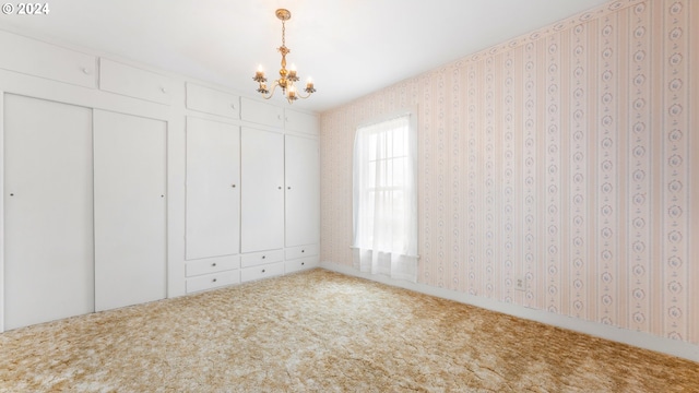 unfurnished bedroom featuring an inviting chandelier, carpet floors, a closet, and wallpapered walls