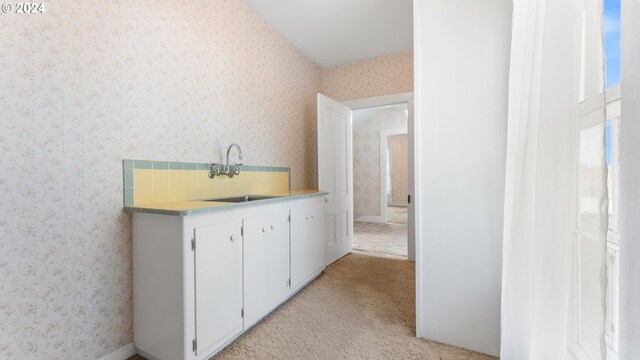 interior space with light colored carpet, wallpapered walls, and a sink