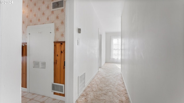hallway with baseboards, visible vents, and wallpapered walls