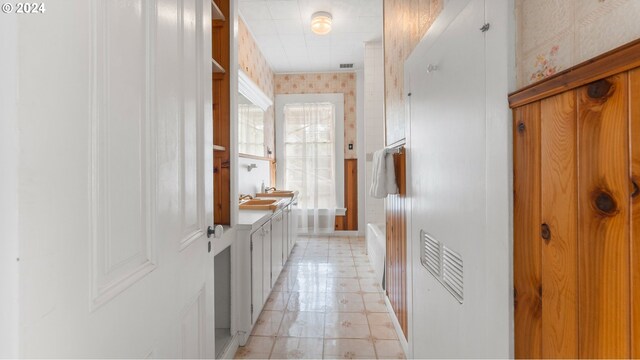 corridor with wallpapered walls, visible vents, and baseboards