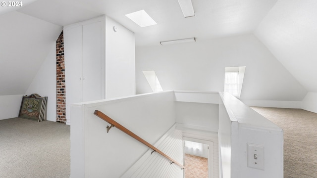 stairs with carpet flooring and vaulted ceiling with skylight