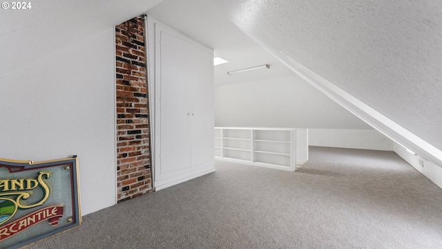 bonus room featuring carpet flooring, built in shelves, vaulted ceiling, and a textured ceiling