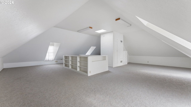 additional living space featuring carpet, a textured ceiling, and vaulted ceiling with skylight