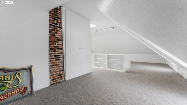 additional living space with lofted ceiling, carpet flooring, and a textured ceiling