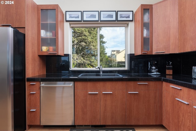 kitchen with dark stone countertops, tasteful backsplash, appliances with stainless steel finishes, and sink