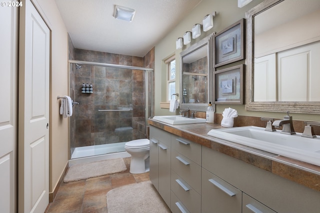 bathroom with toilet, vanity, a textured ceiling, and a shower with door