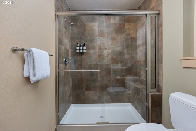 bathroom with a shower with shower door and toilet