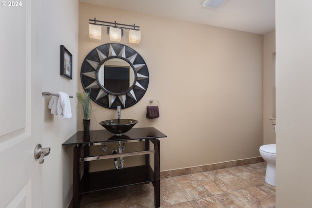 2777 NW Neptune Ave, Lincoln City, OR 97367 - bathroom featuring a sink, baseboards, toilet, and stone finish flooring
