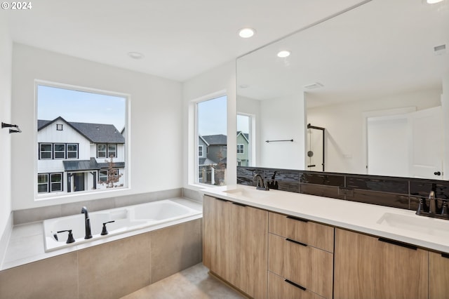 bathroom with vanity and a relaxing tiled tub