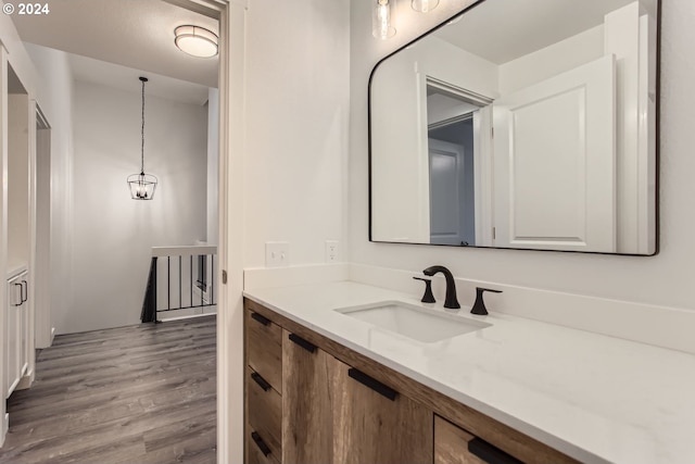 bathroom with vanity, wood-type flooring, and an inviting chandelier