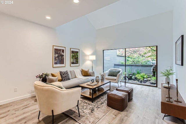 living room with high vaulted ceiling and light hardwood / wood-style flooring