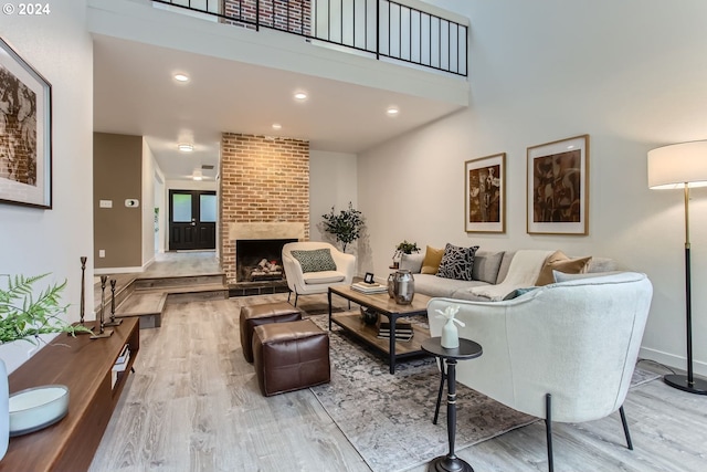 living room featuring light wood-type flooring and a brick fireplace