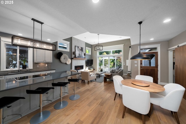 dining space with a textured ceiling, an inviting chandelier, light wood-type flooring, and sink