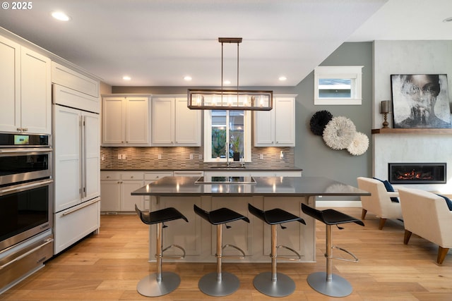 kitchen with a kitchen island, pendant lighting, paneled refrigerator, and tasteful backsplash