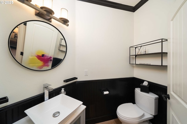 bathroom with sink, toilet, crown molding, and wooden walls