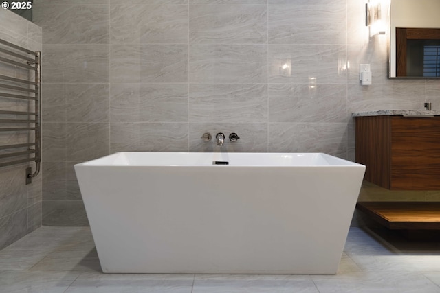 bathroom featuring vanity, tile walls, a bathing tub, and radiator heating unit