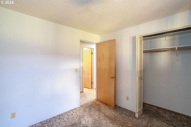 unfurnished bedroom featuring a textured ceiling, carpet floors, and a closet