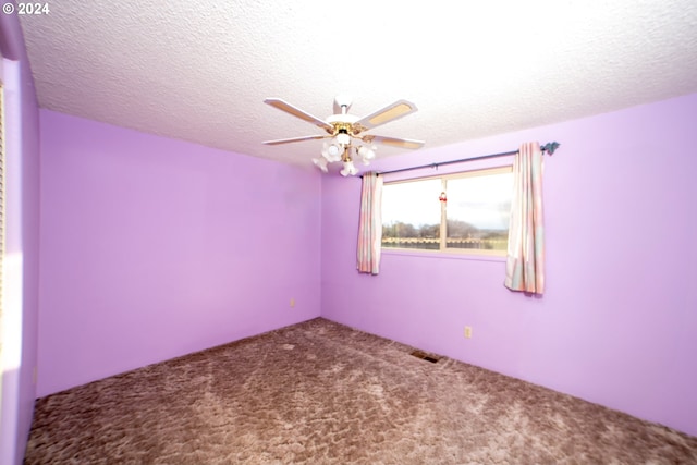 empty room with ceiling fan, carpet floors, and a textured ceiling