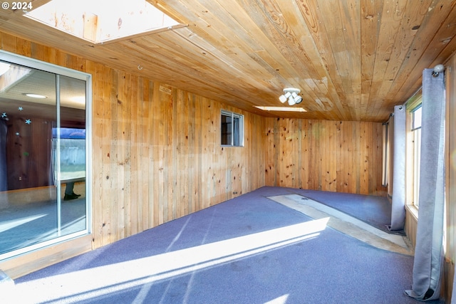 carpeted spare room with wooden walls and wood ceiling