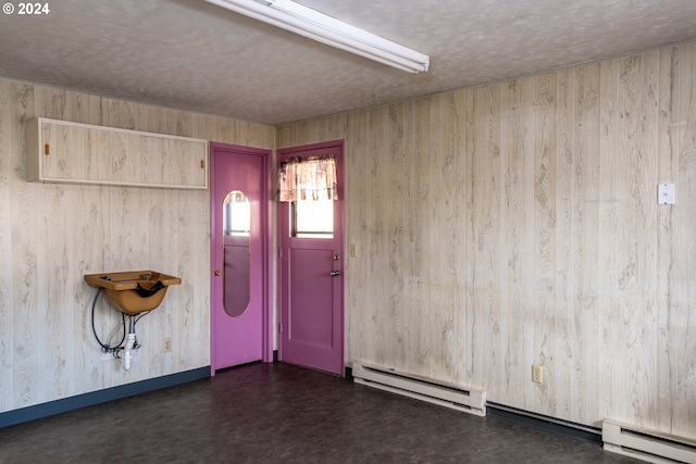 unfurnished room featuring a baseboard heating unit and wood walls