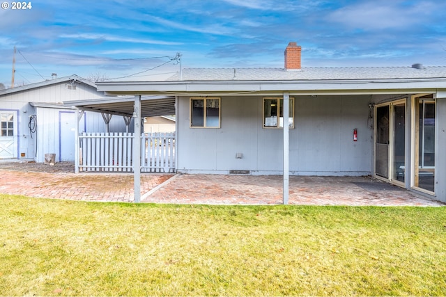 back of property with a lawn and a patio