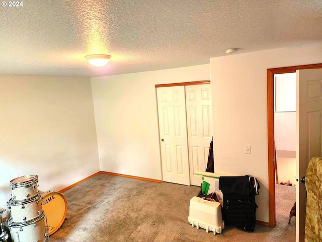 carpeted bedroom with a textured ceiling, a closet, and baseboards