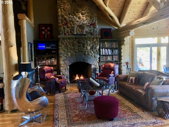 living room featuring a stone fireplace, hardwood / wood-style floors, beamed ceiling, and wooden ceiling