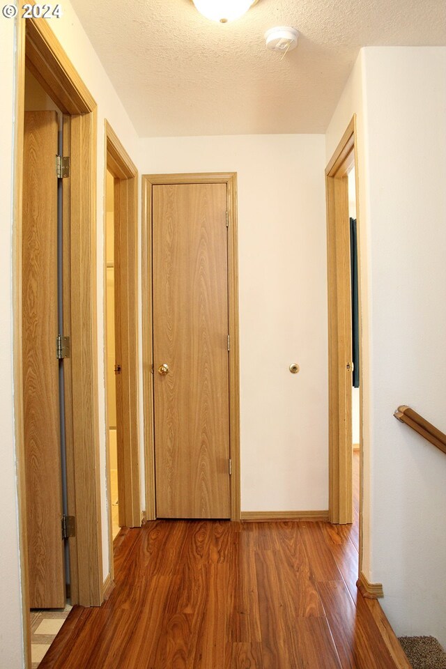 corridor with wood-type flooring and a textured ceiling