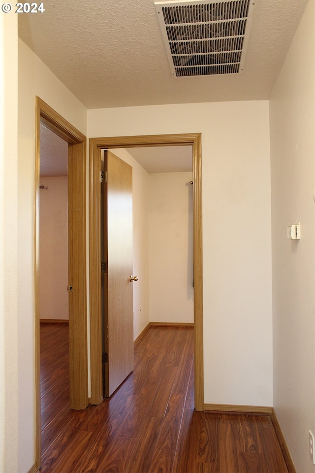 corridor with dark wood-type flooring and a textured ceiling