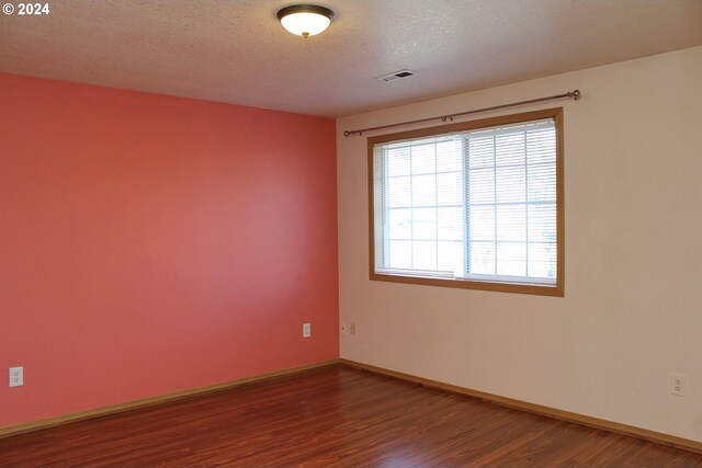 unfurnished room with dark hardwood / wood-style flooring and a textured ceiling