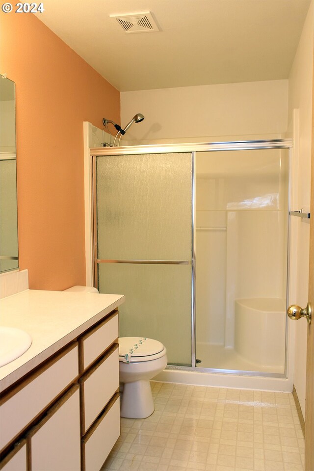 bathroom featuring toilet, an enclosed shower, and vanity