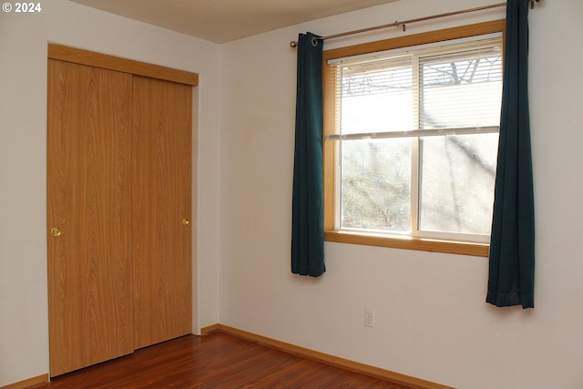 unfurnished bedroom with a closet and dark wood-type flooring